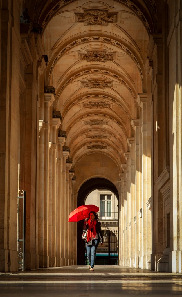 Red Umbrella Parisian woman walking with red umbrella near the Louvre.