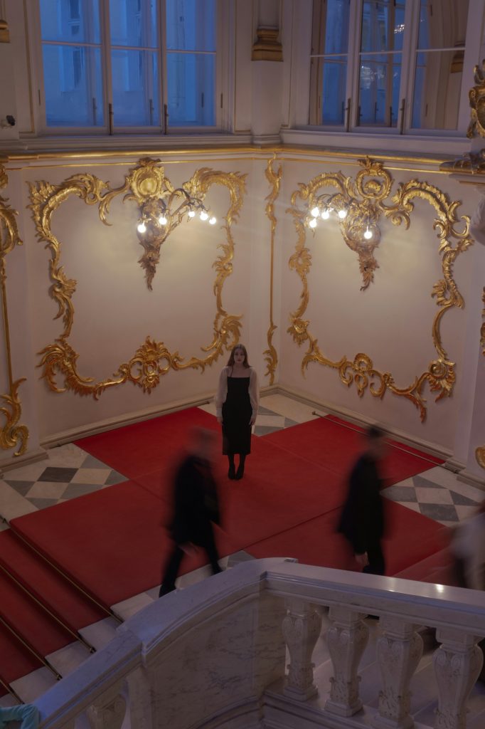 A person standing on a red carpet at the corner of a staircase in the State Hermitage Museum