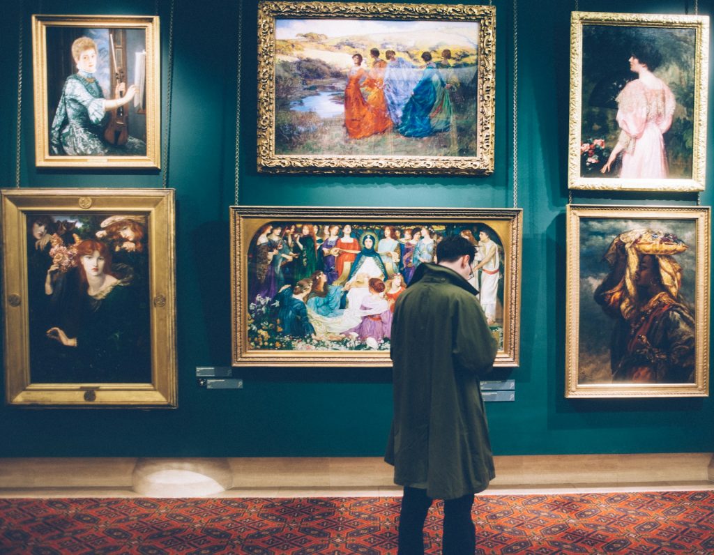 Man standing in front of paintings in an art gallery in America