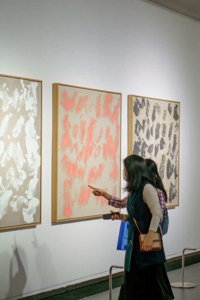 Two women standing in front of paintings in an art gallery in America