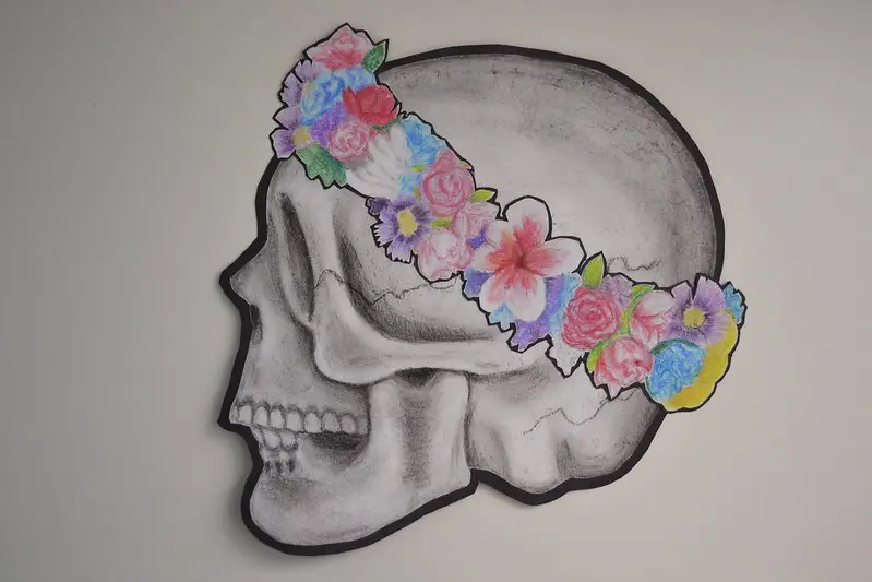 A drawing of a skull with a flower wreath
